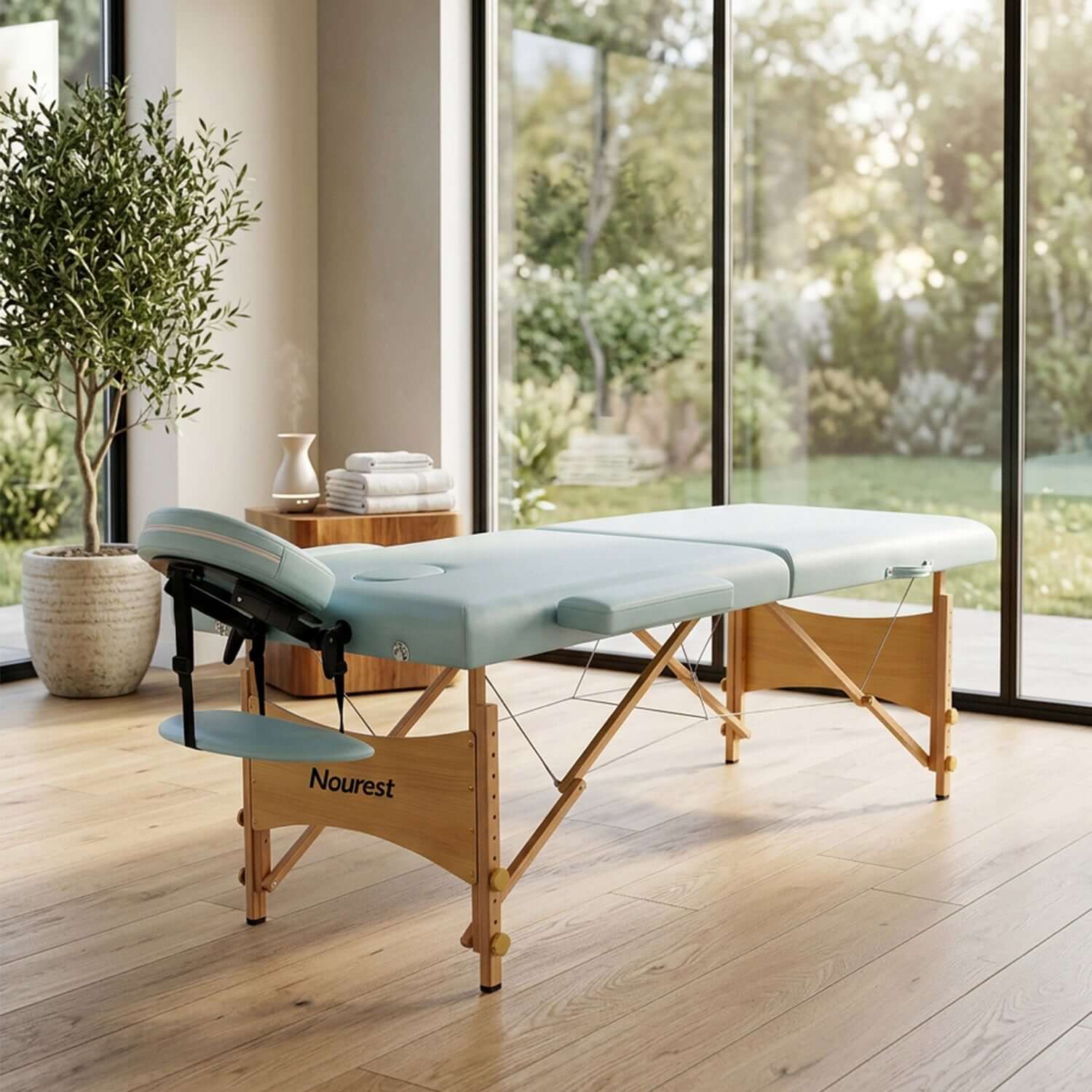Nourest portable foldable massage bed set up in a stylish interior with large windows and greenery around.