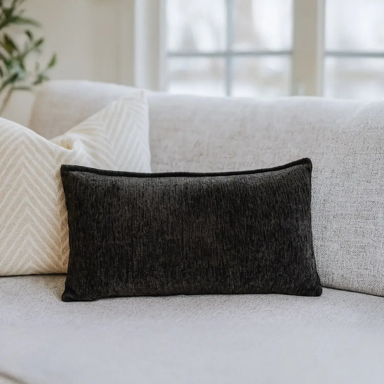 Nourest S1 massage pillow with wireless hot compress, stylish black design on a sofa.