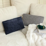 Two stylish pillows in navy and gray on a cozy sofa, surrounded by a soft white blanket and a green coffee cup.