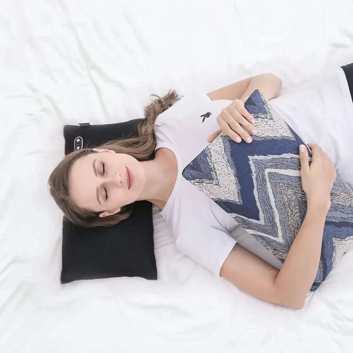 woman relaxing with Nourest S1 massage pillow and a decorative cushion on a bed.